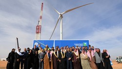 Saudi Aramco and GE executives and local dignitaries and business leaders pose in front of the first wind energy turbine in Turaif.