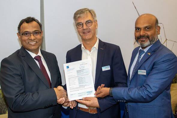 Lars Weigel (Mitte) und Dr. Kumaravel Rathinavel (rechts) überreichen Milind Kulkarni (links) das Typenzertifikat für die neue 5,2 MW Windenergieanlage von Adani (Bild: WindGuard Certification)
